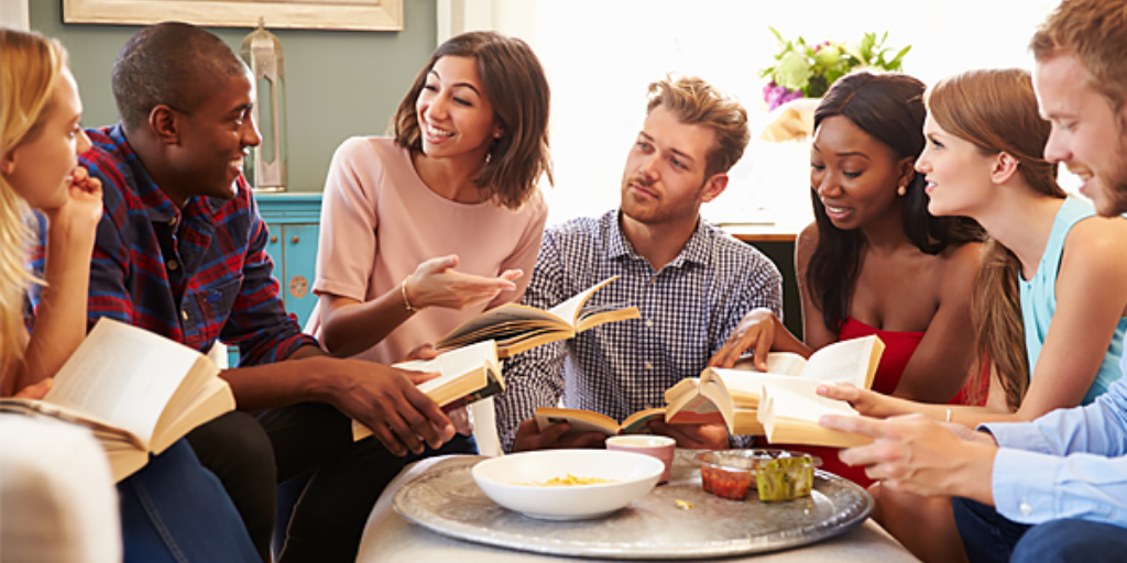 Picture is of a group of adults reading a book and talking around a table. Book clubs are not limited to either in-person and virtual. Here are some tips on how to find one that fits your interests. 